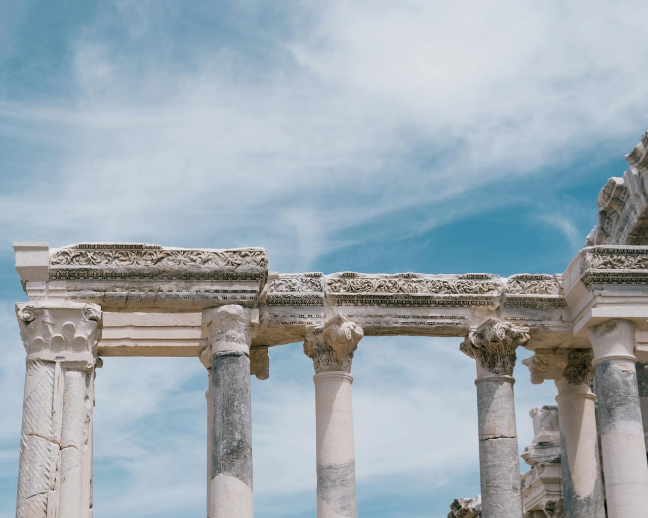 Orchestrating Territorial Mobility: How Small DMOs Future-Proof Mountain Destinations Through Eco-Mobility Classical ruins in Antalya, Türkiye, with intricate columns against a bright blue sky.